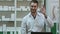 Smiling male pharmacist in white coat showing thumbs up and okey hands gesture