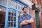 Smiling Male Small Business Owner Wearing Apron Standing Outside Shop On Local High Street