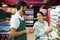 Smiling male staff assisting a woman with grocery shopping