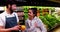 Smiling male staff assisting a woman with grocery shopping