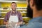 Smiling male staff holding a meat packet at counter