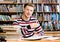 Smiling male student with open book working in a library