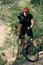 smiling male trial biker in protective helmet riding on mountain bicycle