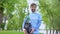 Smiling male volunteer holding green tree seedling standing in forest, eco event