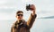 Smiling man doing self-portrait on coastline