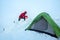 Smiling man dressed red warm mountaineering down jacket making the protective wall from snow bricks around camp tent on glacier