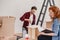 Smiling man folding furniture while woman unpacking stuff after relocation