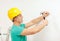 Smiling man in helmet hammering nail in wall