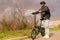 Smiling man with helmet and his electric bicycle at sunset. Commuter and new transportation concept. Green energy concept