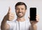 Smiling Man Holding Blank Cellphone Gesturing Thumbs Up, Isolated