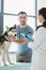 smiling man holding husky and female veterinarian writing