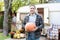 Smiling Man holds big orange pumpkin. Halloween preparation. Happy Farmer holding ripe pumpkin in hands in countryside