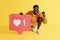 Smiling man with like icon, heart pinata on yellow background