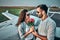 Smiling man is looking on nice lady with flowers over private plane on background