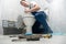 Smiling man plumber in uniform repairing toilet bowl using instrument kit looks happy showing like sign professional repair