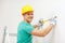 Smiling man in protective helmet measuring wall