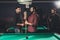 smiling man rubbing cue with chalk beside pool table at bar