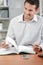 Smiling man sat at desk turning pages notebook