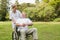 Smiling man sitting in a wheelchair talking with his nurse pushing him