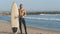 Smiling man surfer shows shaka gesture standing on the shore