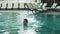 Smiling man swimming at modern hotel. Sexy guy bathing at luxury pool indoor.