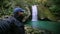 Smiling man is taking selfie against waterfall and small lake in autumn forest