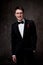 Smiling man in tuxedo on grey background