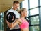 Smiling man and woman with barbell in gym