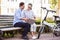 Smiling man and woman talking in park with a laptop