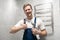 Smiling man worker in uniform with spanner in his hand shows like sign looks happy after doing successful professional repair