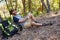 Smiling man writing on notepad while resting on tree trunk