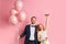 Smiling married caucasian couple with pink air balloons isolated over pink background