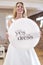 Smiling Mature Bride Planning Wedding In Bridal Store Holding Yes To The Dress Sign