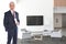 Smiling Mature Businessman standing in a modern office building lobby with Flat Screen Monitor. He is holding a rolled up document