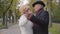 Smiling mature Caucasian couple dancing on the alley in the autumn park. Positive senior family dating outdoors.