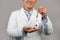 Smiling mature chinese guy therapist in white coat show sos alarm button, isolated on gray background, cropped