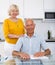 Smiling mature couple with documents sitting at table in home