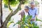 Smiling mature couple engaged and watering plant in garden front home.