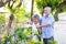 Smiling mature couple engaged and watering plant in garden front home.