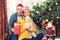 Smiling mature couple wearing santa hat embracing each other and holding dog sharing xmas presents