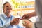 Smiling mature customer paying through credit card at restaurant