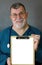 Smiling Mature Doctor Displays a Blank Clipboard