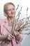 Smiling mature, elegant woman in pink blazer.  holds a pussy willow for Easter. Happy Easter concept