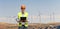 Smiling mature engineer standing on a wind turbine farm