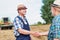 Smiling mature farmer shaking hands with senior famer in field