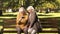 Smiling mature ladies watching photos or news on smartphone sitting in park