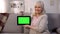 Smiling mature lady holding green screen tablet in hands, easy banking, shopping