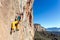 Smiling mature male extreme Climber hanging on rocky wall easy