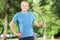 Smiling mature man with headphones holding a hula hoop in park