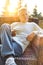 Smiling mature man holding drink while sitting on wicker chair at patio